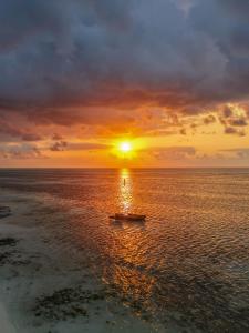 a boat in the ocean with a sunset at Juana Ocean Villas in Makunduchi