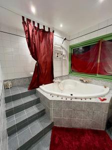 a bathroom with a tub and a red curtain at Le Mas des Vignes parisian hacienda in Rueil-Malmaison