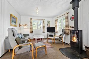 ein Wohnzimmer mit Kamin und einer Couch und Stühlen in der Unterkunft BV377 Blåvand - Fynsland 7 in Blåvand