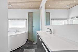ein Badezimmer mit Badewanne, Waschbecken und Spiegel in der Unterkunft BV377 Blåvand - Fynsland 7 in Blåvand + 26 Fotos