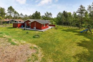 ein rotes Haus in einem Hof mit einem Spielplatz in der Unterkunft BV377 Blåvand - Fynsland 7 in Blåvand