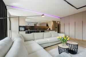 Una sala de estar con un sofá blanco y una cocina. en LupoApartments Premium Łazowskiego, Parking, Dostęp na Kod, 3 Sypialnie, en Łódź
