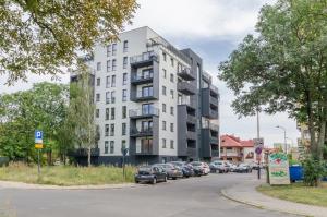 un edificio blanco alto con coches aparcados en la calle en LupoApartments Premium Łazowskiego, Parking, Dostęp na Kod, 3 Sypialnie, en Łódź