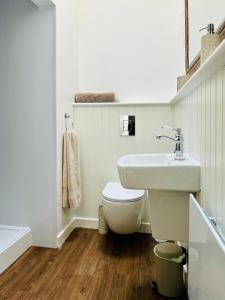 a white bathroom with a toilet and a sink at The Green Room in Tideswell