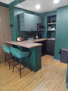 a kitchen with green walls and a counter with stools at The Green Room in Tideswell +15 photos
