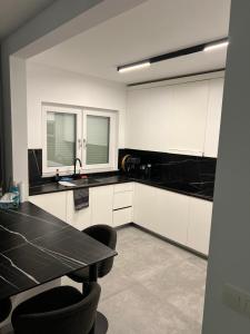a kitchen with black and white cabinets and a table at Heel Appartement 90m2 met 2 slaapkamers woonkamer Keuken badkamer privé garage in Sint-Truiden
