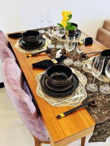 a wooden table with plates and wine glasses on it at YAKA Residences - Trizen Luxury Apartments in Colombo