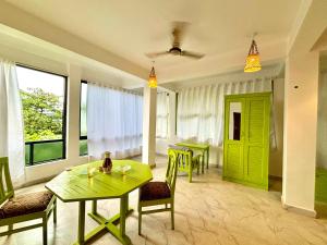 a living room with green doors and a table and chairs at Dreamy vibe Stays in Morjim
