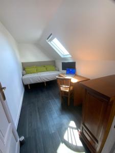 a small room with a bed and a desk with a laptop at Maison du Homard Bleu in Audierne