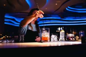 a woman is stirring a drink in a bar at Villa Viva - ein Haus das Brunnen baut in Hamburg
