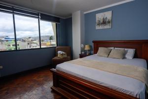 a bedroom with a bed and a large window at Hermoso y cómodo loft con vista a los nevados in Riobamba