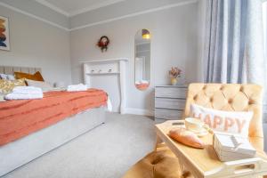 a bedroom with a bed and a chair and a table at Cairnhill House - cosy 3 bedroom in Airdrie