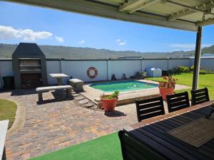 eine Terrasse mit Pool, Tisch und Stühlen in der Unterkunft Bee Unique in Sedgefield