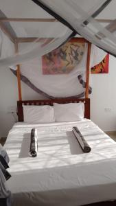 a bed with a white sheets and a bottle on it at Kijani unique home Malindi in Malindi +23 photos