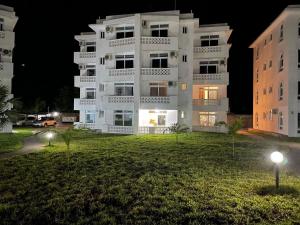 a white apartment building at night with a green yard at Kijani unique home Malindi in Malindi
