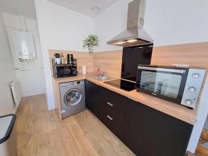 a kitchen with a microwave and a washing machine at Le 84bis, maison, proche gare, parking, Netflix in Laval +14 photos