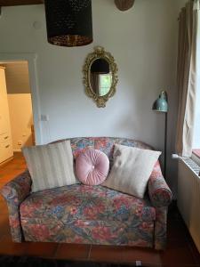 un sofá en la sala de estar con espejo en Reetdachhaus am See Ostfriesland, en Leezdorf