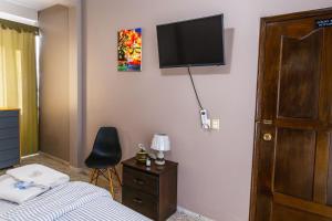 Un dormitorio con una cama y un televisor en la pared. en Go Bed & Breakfast, en San Pedro Sula