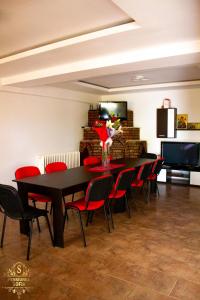 a dining room with a black table and red chairs at Casa Sofia in Murighiol