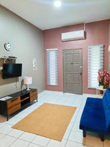 Una sala de estar con un sofá azul y un televisor en Adriana RH Homestay 3Bedroom 2Bathroom, en Kampong Bukit Rambai