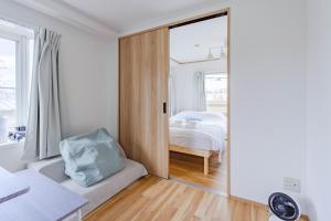 a white bedroom with a bed and a window at IJIRIGoodStay in Fukuoka