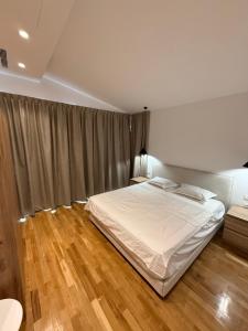 a bedroom with a white bed and wooden floors at Luxury Villa Silente in Mjull-Bethore