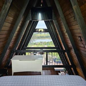 a bedroom with a white bed and a large window at Wiri House na beira da Lagoa Doce in Imbituba