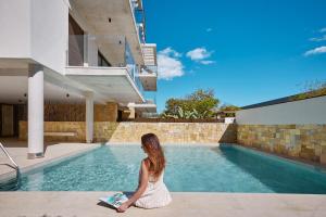 Eine Frau in einem weißen Kleid neben einem Pool in der Unterkunft Luxury Apartment Tamana Burgundy - by Welcomely in Jávea + 14 Fotos