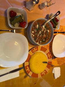 a table with plates of food and bowls of soup at Norica Guesthouse in Gura Rîului