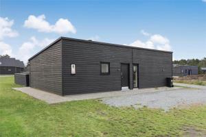 una casa nera su un campo con un prato di 0347-Romo-Vestergade-353 a Sønderby