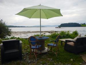 a table with an umbrella and two chairs and a television at Adrigole Bay Studio Apartment in Adrigole