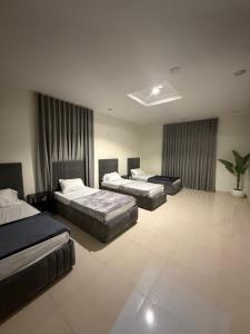 a bedroom with three beds and a potted plant at استديو كلاود غرفتين نوم in Al Baha