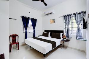 um quarto branco com uma cama e uma cadeira em Hotel O Elegant Residency Vandalur Zoo em Chennai