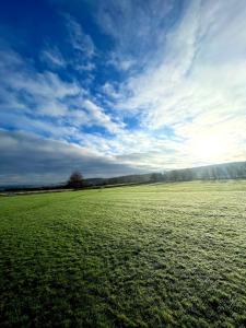 a large green field with a blue sky and clouds at The Tiny Tea Room in Ridingmill