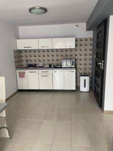 a kitchen with white cabinets and a tile floor at Nad jeziorem in Żywiec