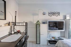 a room with a desk with a computer and a tv at SleepOver Wembley in London