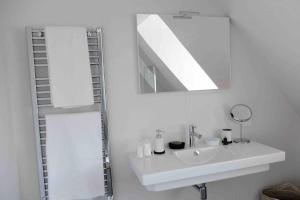 a white bathroom with a sink and a mirror at Loft d'architecte - vue sur port et deco vintage in Paimpol +18 photos
