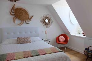 a bedroom with a bed and a red chair at Loft d'architecte - vue sur port et deco vintage in Paimpol