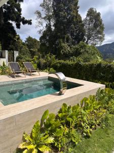a swimming pool with two chairs in a garden at The White Horse, Private Pool, Sauna and Valley View in Cameron Highlands