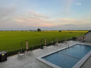 a swimming pool with tables and chairs next to a field at MI LE GARDEN Chalet in Sekinchan