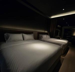 two twin beds in a dark room with at Black Martini Premium Suite in Tanjong Tokong