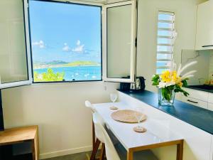 a kitchen with a table with two wine glasses and a window at Studio Panoramic vue mer époustouflante et piscine à débordement in Grand Case
