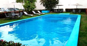 Una gran piscina azul con sillas y mesas. en Hotel Arcos Aeropuerto, en Veracruz