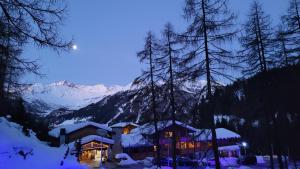 a ski lodge in the snow at night at Boscone Suite Hotel in Madesimo