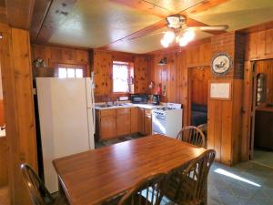a kitchen with a table and a white refrigerator at Old Stoney's Musky - Big Arbor Vitae Lake in Arbor Vitae