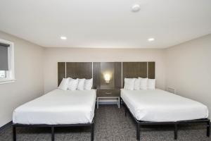 two beds in a hotel room with white sheets at Settle Inn in Sioux Falls