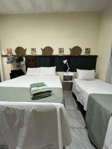 a room with two beds with white and green sheets at Hotel Pousada Casa Verde in Cordisburgo