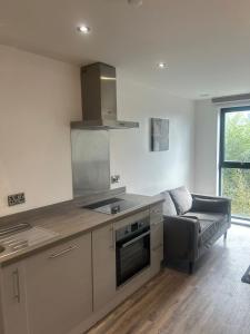 a kitchen with a stove and a couch in a room at Near Old Trafford & Media City 2BR Flat in Manchester