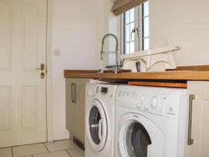 a white washing machine in a kitchen with a sink at Atlantic View Apartment in Bude