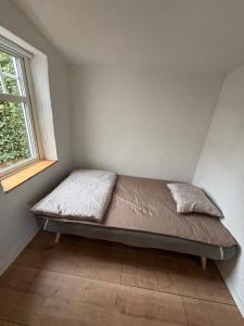 a bed in a corner of a room with a window at Gäststugan in Ystad